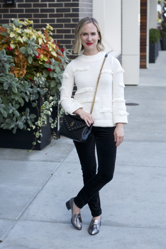 cream fringe sweater, velvet skinny jeans, YSL college bag, metallic loafers